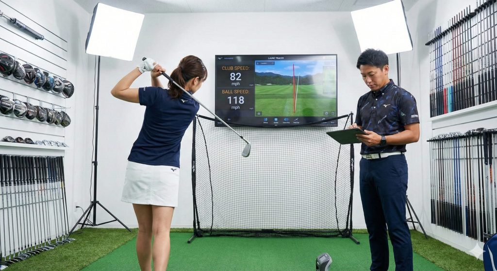 フィッティングセンターで弾道測定器を使いアイアンを試打する女性
